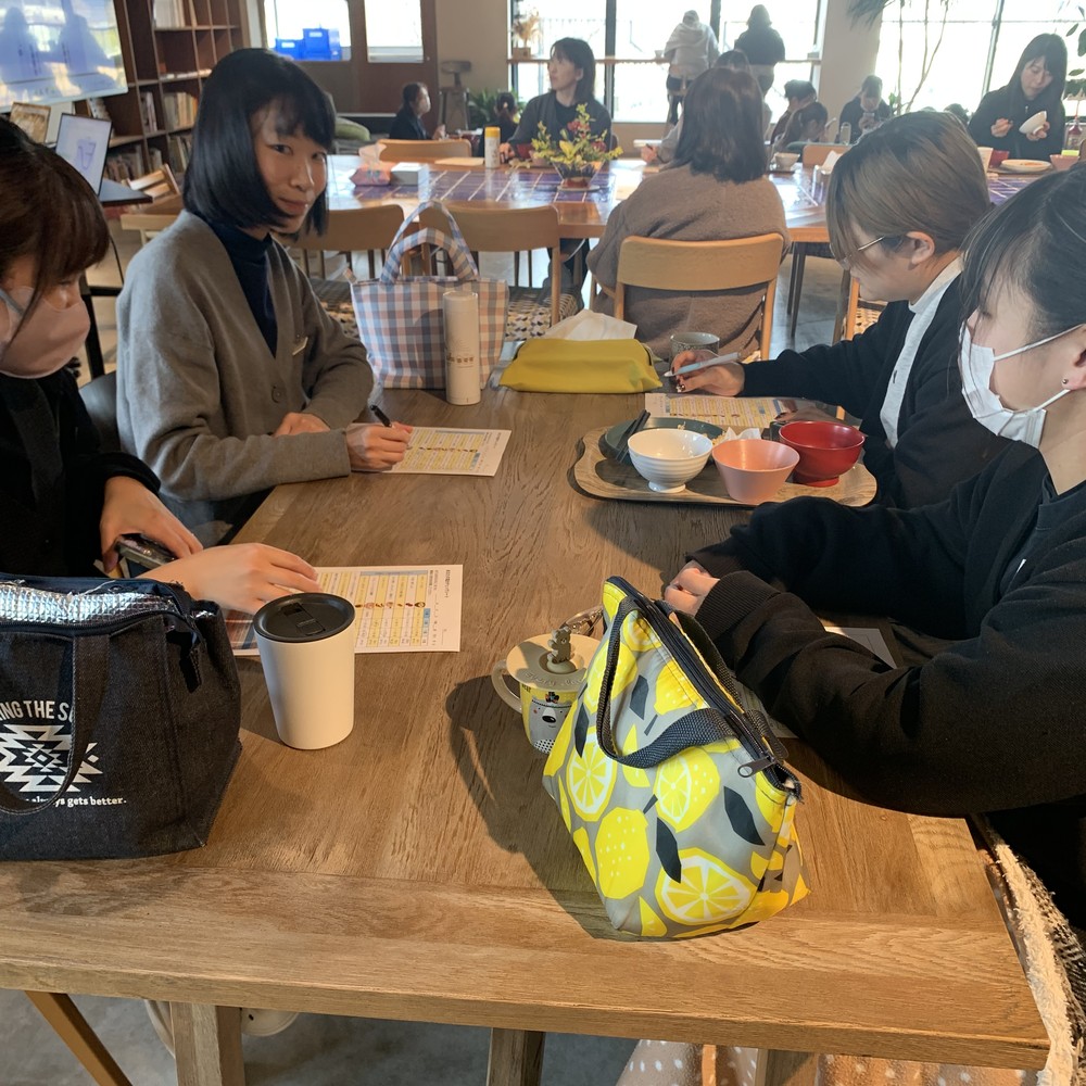 社員食堂のテーブルを囲んで昼食をとる社員